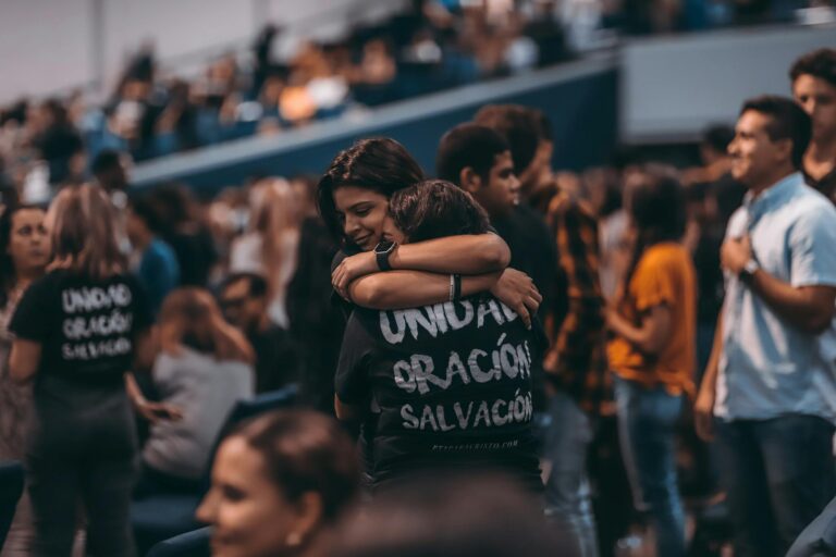 A heartfelt embrace among people at a crowded indoor event fostering unity and connection.